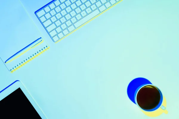 Blue toned picture of coffee cup, empty textbook, pen, digital tablet and computer keyboard — Stock Photo