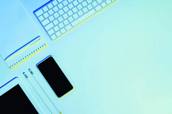 Blue toned picture of pencils, textbook, pen, digital tablet, smartphone and computer keyboard — Stock Photo