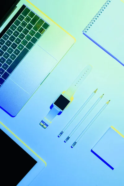 Foto tonificada azul del ordenador portátil, tableta digital, reloj inteligente, lápices, libro de texto y nota adhesiva - foto de stock