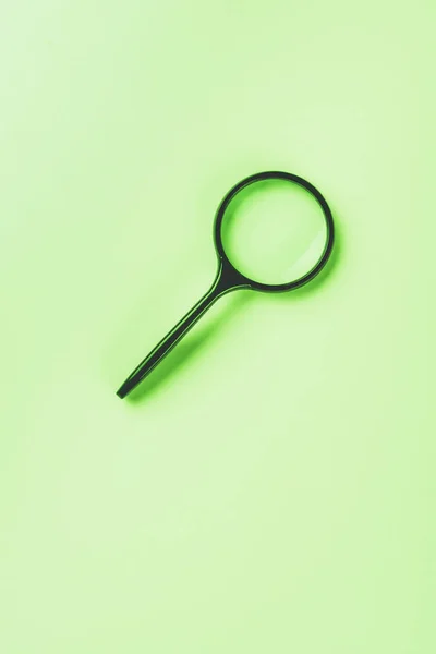 Closeup shot of magnifying glass on green background — Stock Photo