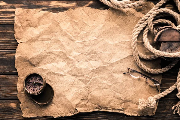 Top view of blank crumpled paper with compass and rope on rustic wooden surface — Stock Photo