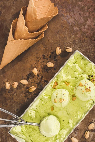 Vue du dessus de la crème glacée aux pistaches avec cuillère et cônes de crème glacée sur la table — Photo de stock