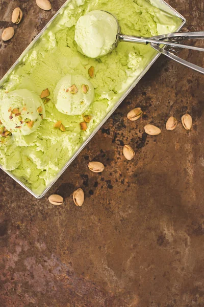 Elevated view of pistachio ice cream with scoop and pistachios on table — Stock Photo