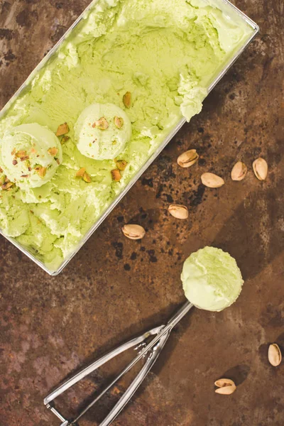 Vue du dessus de la crème glacée aux pistaches avec cuillère et pistaches sur la table — Photo de stock