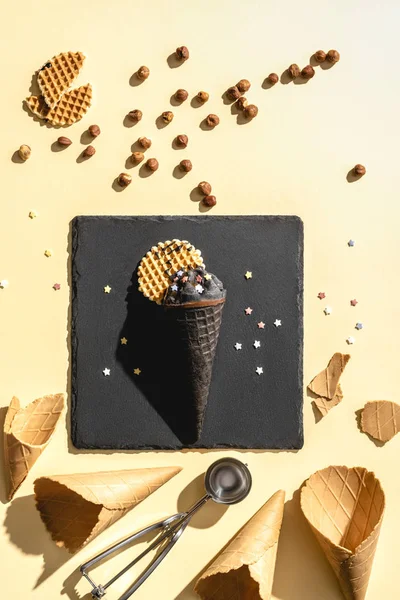 Blick von oben auf Schokoladenschwarzes Eis und leere Eistüten auf gelb — Stockfoto