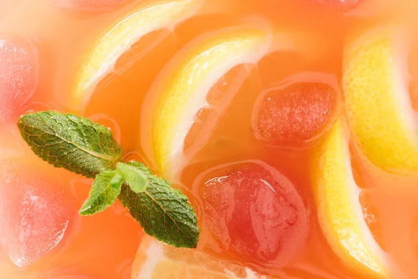 Close up view of fresh cocktail with mint, ice cubes and lemon pieces background — Stock Photo