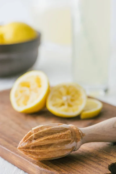 Selective focus of wooden pestle and lemon pieces on wooden cutting board for making lemonade — Stock Photo