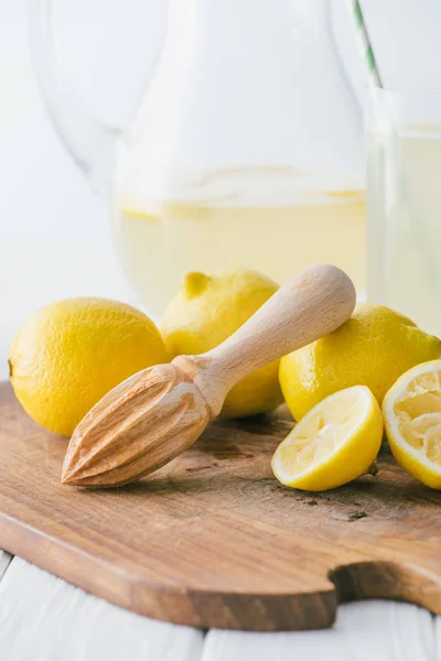 Selective focus of wooden pestle and lemon pieces on wooden cutting board for making lemonade — Stock Photo