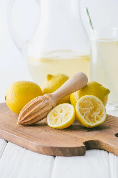 Selektiver Fokus von Zitronen und Holzpresse auf Schneidebrett zur Herstellung frischer Limonade auf weißer Holzplatte — Stockfoto
