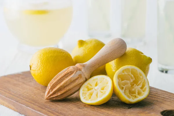 Vista de cerca de limones y mortero de madera para hacer limonada en la tabla de cortar - foto de stock