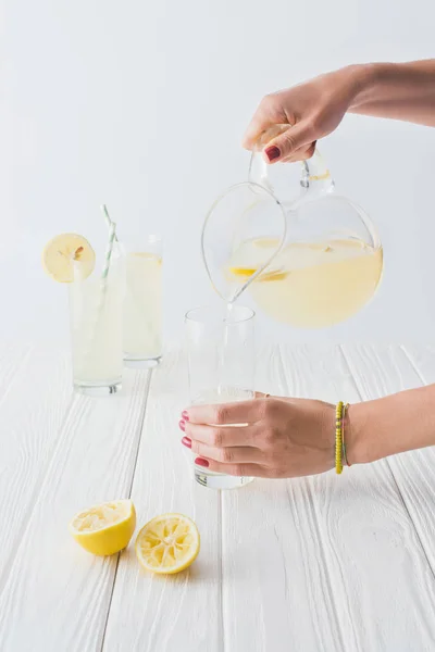 Schnappschuss einer Frau, die Limonade in Glas auf grauem Hintergrund gießt — Stockfoto