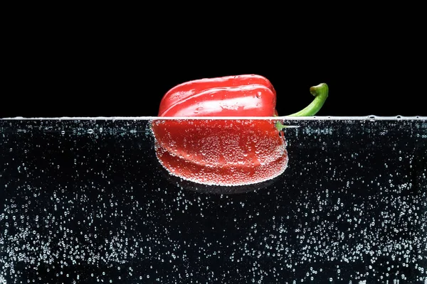 Закрыть вид спелых красный перец колокол в воде изолированы на черном — стоковое фото