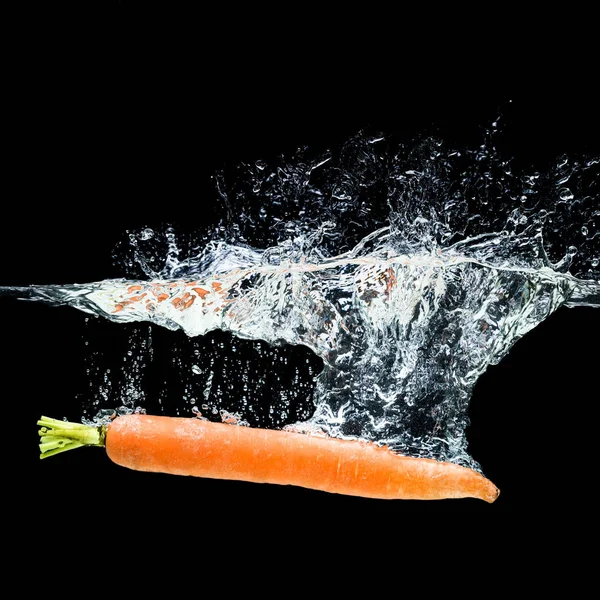 Закрытый вид моркови в воде, изолированной на черном — стоковое фото