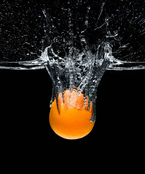 Close up view of fresh orange citrus fruit falling into water isolated on black — Stock Photo