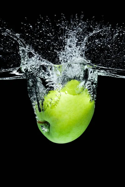Крупним планом вид на зелене яблуко, що падає у воду ізольовано на чорному — стокове фото