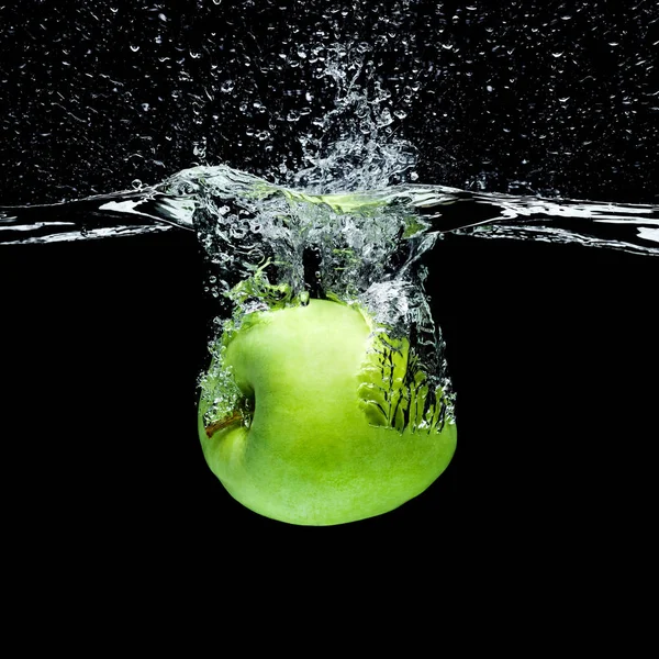 Vue rapprochée de pomme verte tombant dans l'eau isolée sur noir — Photo de stock