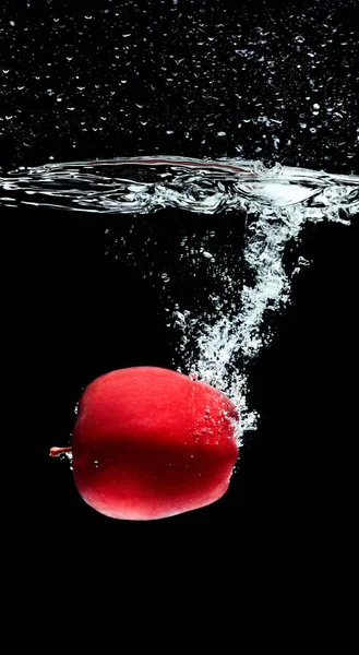 Vue rapprochée de pomme rouge tombant dans l'eau isolée sur noir — Photo de stock