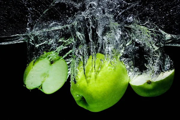 Close up view of fresh green apples in water isolated on black — Stock Photo