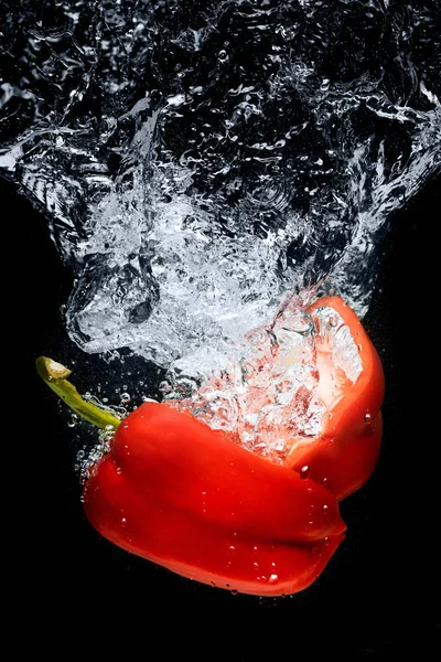 Vista de cerca de las piezas de pimiento en agua aislada en negro - foto de stock