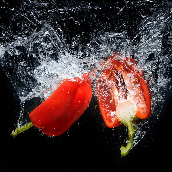 Close up view of bell pepper pieces in water isolated on black — Stock Photo