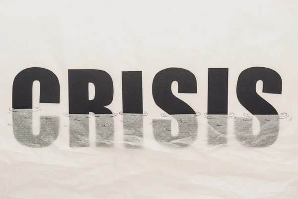 Schwarzes Wort Krise in Papier getaucht symbolisiert Wasser isoliert auf weiß — Stockfoto