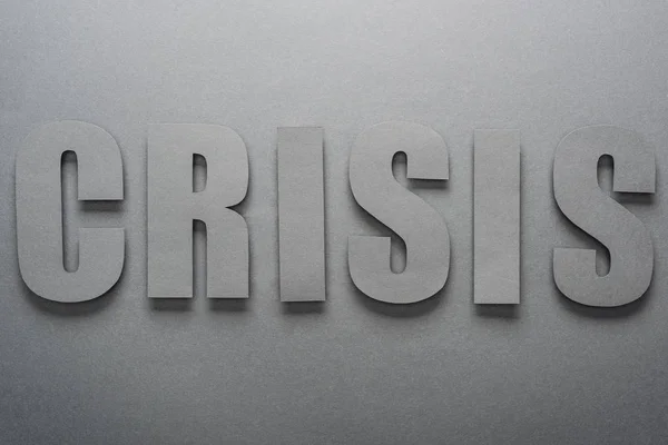 Vista dall'alto di carta taglio parola crisi su sfondo grigio con ombre — Foto stock