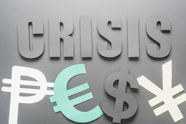 Vista superior de la palabra crisis cerca de peso, euro, dólar y yen símbolos sobre fondo gris con sombra - foto de stock