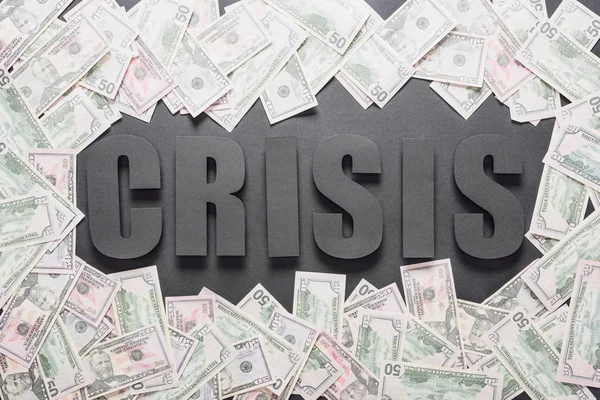 Vista superior de la palabra crisis en el marco de billetes de dólar sobre fondo negro con sombras - foto de stock