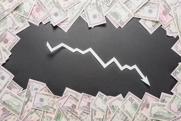 Papier blanc coupe flèche de récession dans le cadre de billets en dollars sur fond noir — Photo de stock