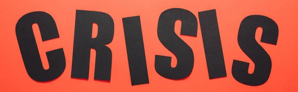 Top view of black paper cut word crisis on red background, panoramic shot — Stock Photo