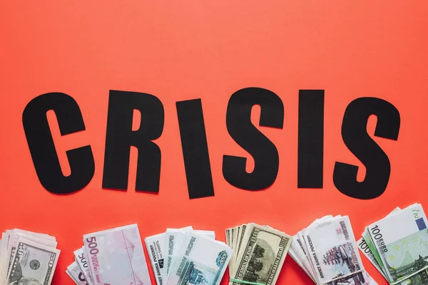 Верхний вид черной бумаги сократить кризис слова около доллара, евро и рубля банкноты на красном фоне — стоковое фото