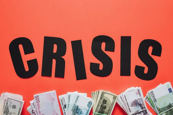 Top view of black paper cut word crisis near dollar, euro and ruble banknotes on red background — Stock Photo