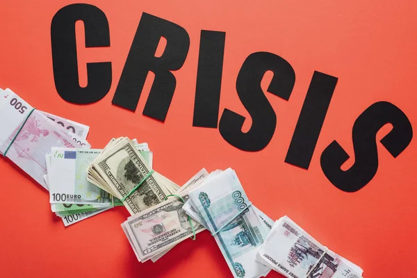 Top view of black paper cut word crisis on dollar, euro and ruble banknotes on red background — Stock Photo