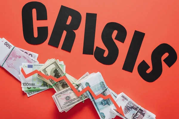 Top view of black paper cut word crisis, and recession arrow on dollar, euro and ruble banknotes on red background — Stock Photo