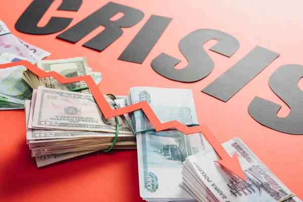 Palabra negra crisis y flecha de recesión en euros, billetes de dólar y rublo sobre fondo rojo con iluminación - foto de stock