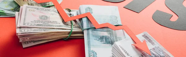 Tiro panorámico de flecha de recesión en euros, billetes de dólar y rublo sobre fondo rojo con iluminación - foto de stock