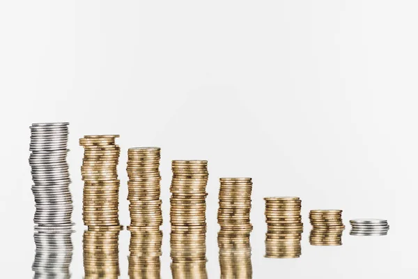 Stacks of silver and golden coins on surface with reflection isolated on white — Stock Photo