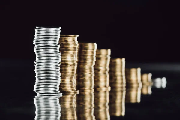 Selektiver Fokus gestapelter Silber- und Goldmünzen auf der Oberfläche mit Reflexion isoliert auf Schwarz — Stock Photo