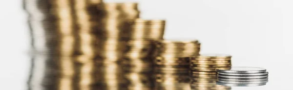 Selective focus of stacked silver and golden coins on surface with reflection isolated on white, panoramic shot — Stock Photo