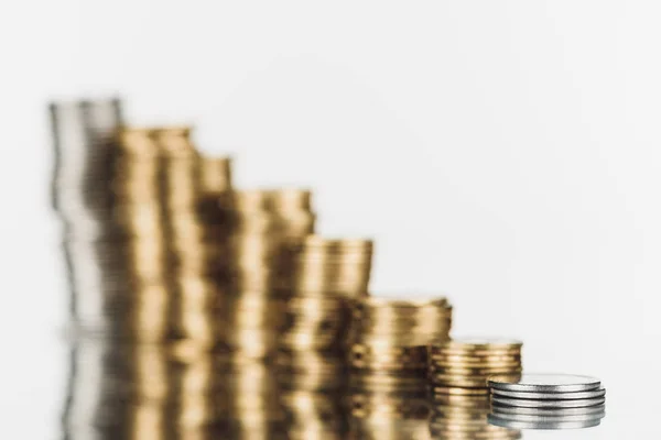 Selective focus of stacked silver and golden coins on surface with reflection isolated on white — Stock Photo