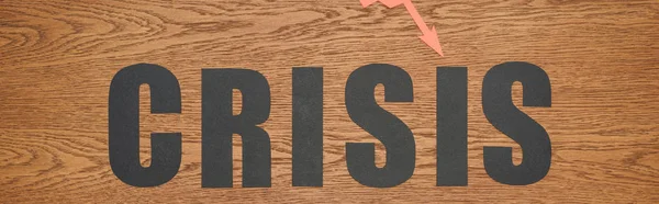 Top view of black paper cut word crisis on wooden desk, panoramic shot — Stock Photo