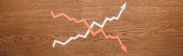 Vista superior del aumento de corte de papel y flechas de recesión en escritorio de madera, plano panorámico - foto de stock