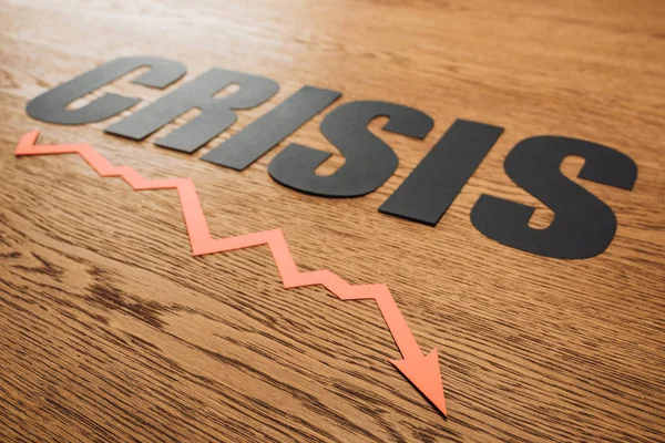 Schwarzer Papierschnitt Wort Krise und Rezession Pfeil auf Holzoberfläche mit Beleuchtung — Stockfoto