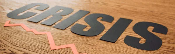 Tiro panorâmico de papel preto cortar crise palavra e diagrama na superfície de madeira com iluminação — Fotografia de Stock