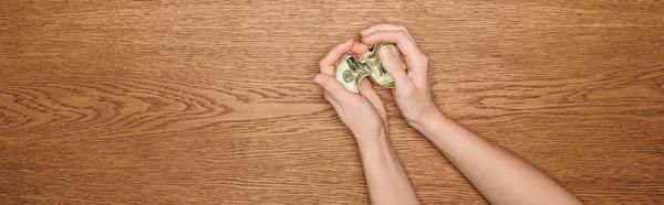 Partial view of female hand with dollar banknote on wooden surface, panoramic shot — Stock Photo