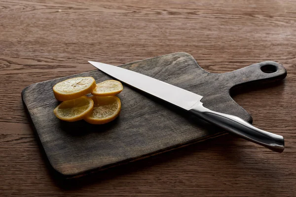 Cut lemon on cutting board with knife on wooden background — Stock Photo