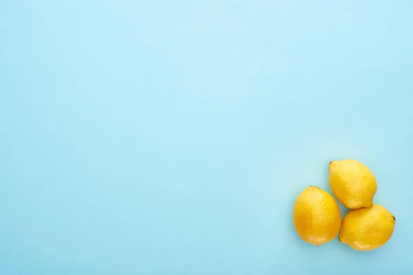 Vue du dessus des citrons jaunes mûrs sur fond bleu avec espace de copie — Photo de stock