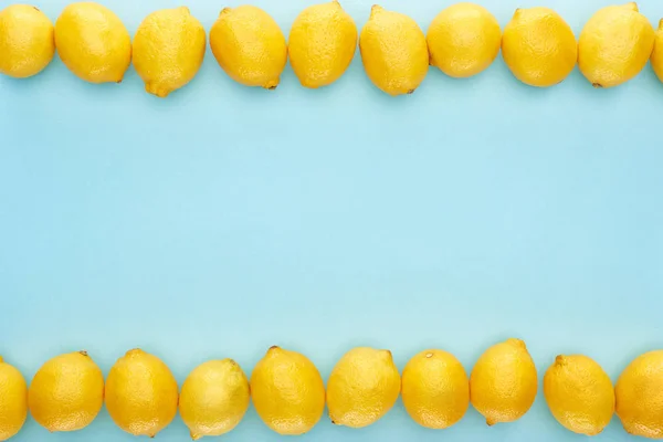 Flat lay com limões amarelos maduros em linhas sobre fundo azul — Fotografia de Stock