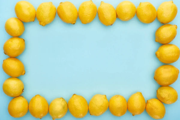 Square frame of ripe yellow lemons on blue background with copy space — Stock Photo