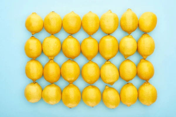 Plat étendu avec des citrons jaunes mûrs sur fond bleu — Photo de stock